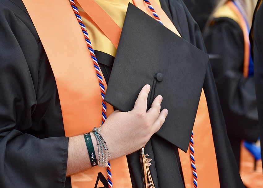 Graduates place their hands over their hearts to recite the Pledge of Allegiance.