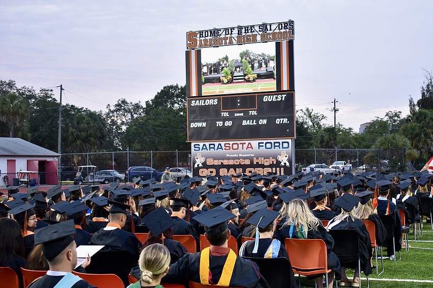 The graduates watch the proceedings on the stadium's big screen.
