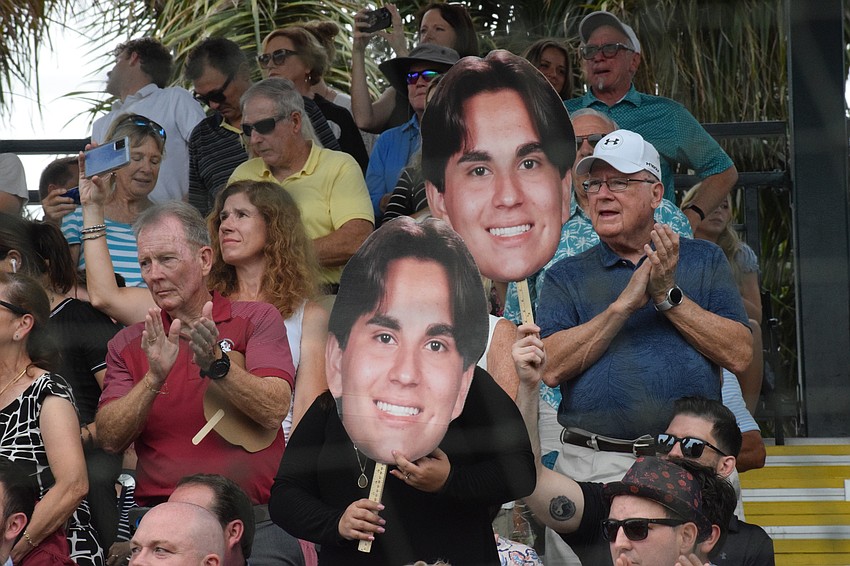 The family of graduate Matthew Boudreau cheer and hold up giant cutouts of his head.