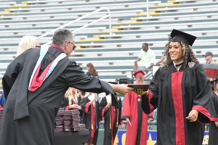 Assistant Principal Matthew Whelden hands Farrah Brito her diploma.