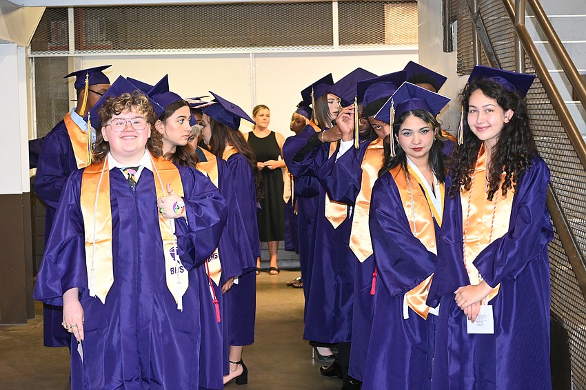 Graduates Logan Davis (left), Larah Pereira Figueroa and Isabela Pizarro line up and prepare to file to their seats.