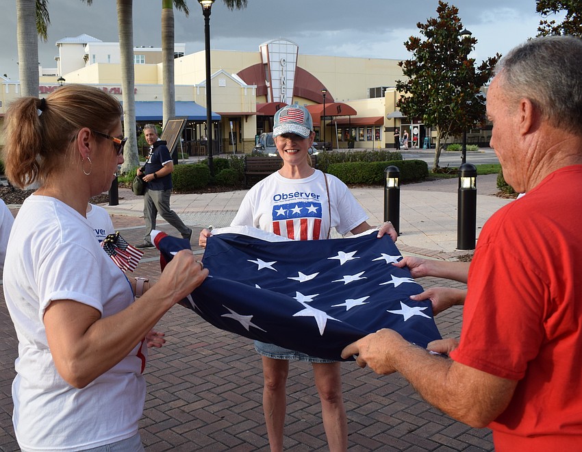 The Observer Media Group's Toni Perren and Emily Walsh join Sarasota's Dave Ruth in folding the American flag as another Tribute to Heroes Parade ends.