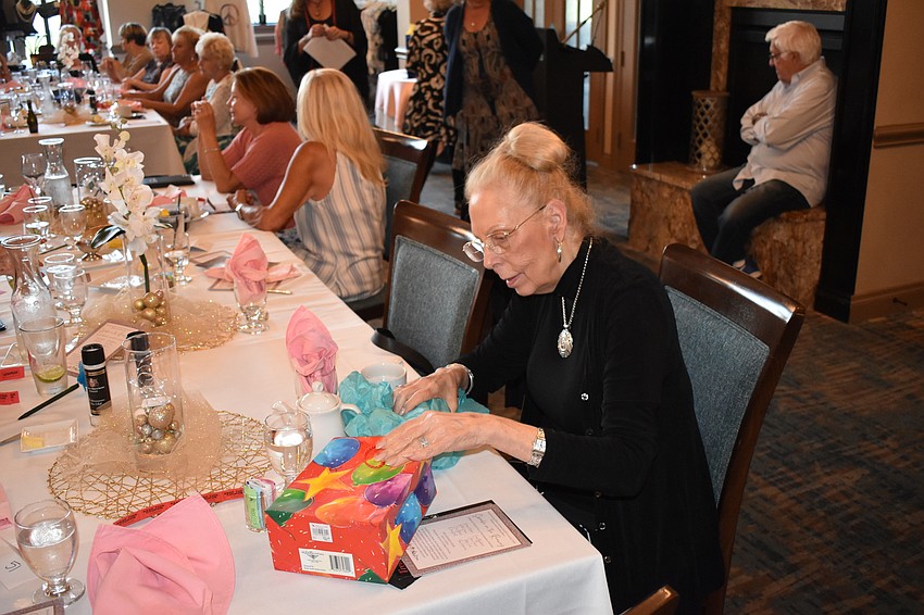Sandy Benh of River Strand unwraps her raffle prize, a candle.