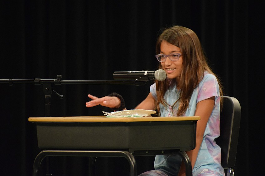 Fifth grader Haylie Thompson gives advice on how to avoid eating green beans during her monologue. Her advice includes hiding them under mashed potatoes or feeding them to a dog.