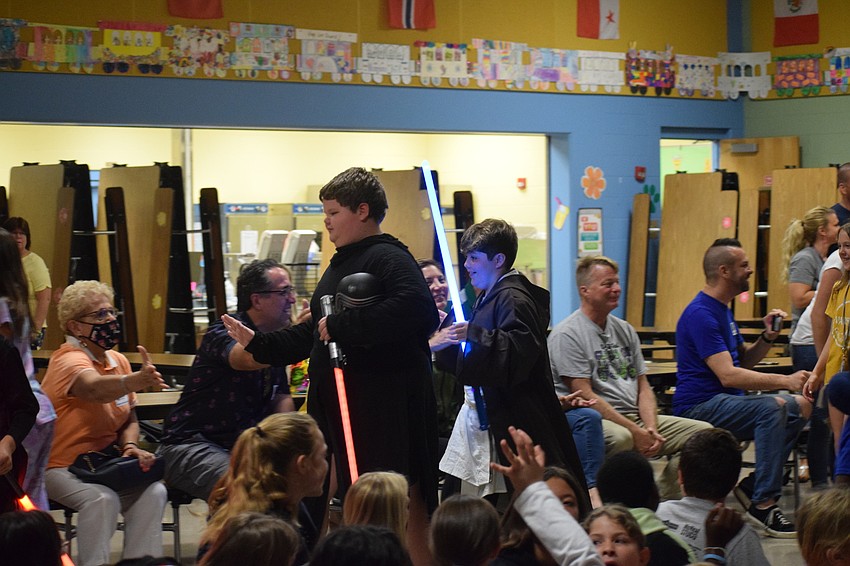 Fifth graders Gus Walsh and Lukas Nantes give audience members high fives as all the performers go around the cafeteria for a final bow.