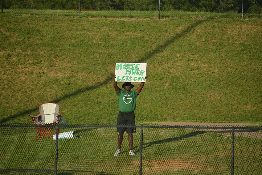 Lakewood Ranch High driver's education teacher and flag football Coach Elijah Weaver stood in the outfield and held up signs of encouragement as the Mustangs took on Lake Brantley High.