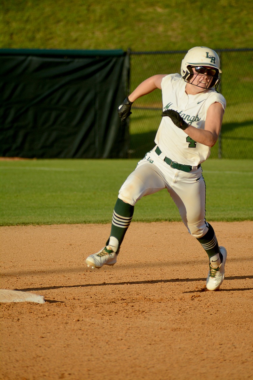 Lakewood Ranch High senior Grace Hogie looks to Coach T.J. Goelz for signals as she rounds second base.