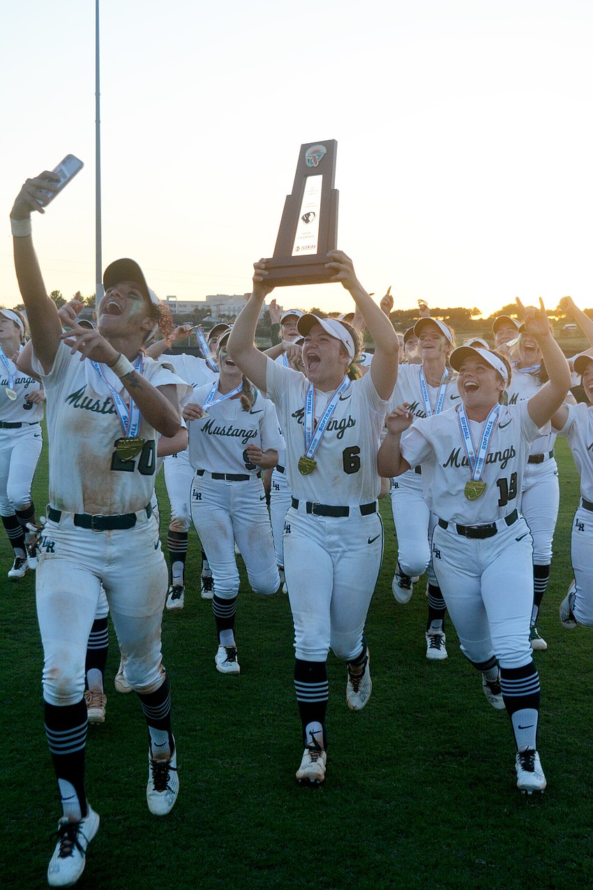 The Mustangs celebrate with their Class 7A state championship trophy after beating Lake Brantley High 8-2.