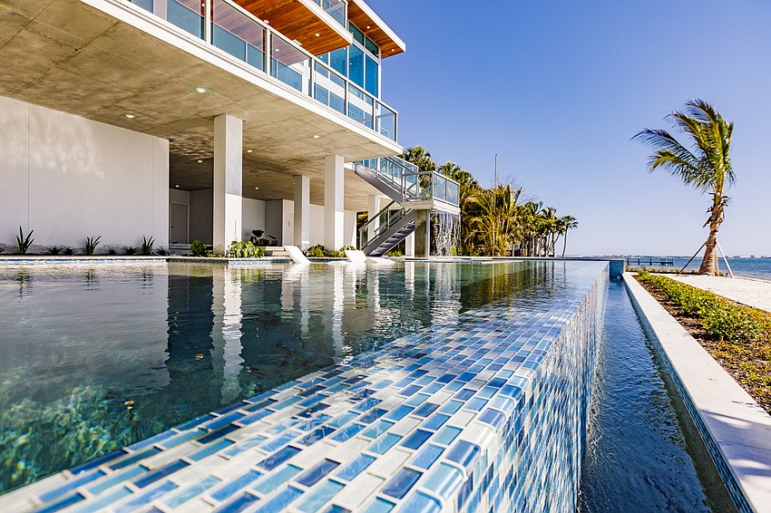 The backyard, overlooking Sarasota Bay and Longboat Key beyond, features as its centerpiece a resort-style swimming pool, a spa, waterfall, in-pool bar and sun lounges and a sunshelf.
