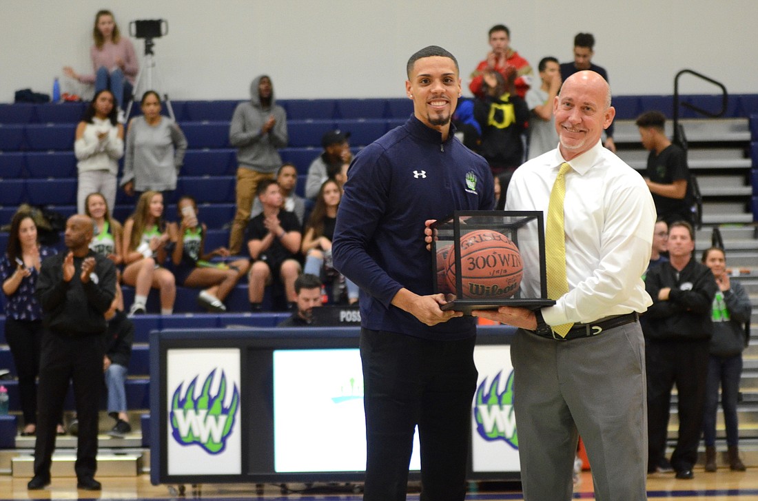 Trey Griseck, left, presented his dad Mark Griseck with a commemorative basketball January 19 to recognize Markâ€™s 300 wins as a head coach.
