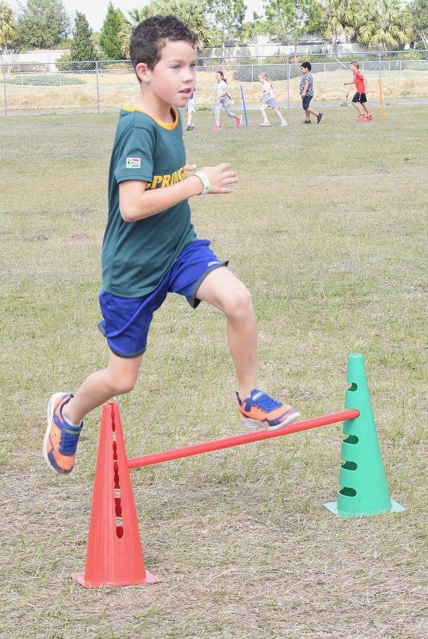 Second grader Liam Odendal jumps over a hurdle as he makes his way around the field during the walkathon.