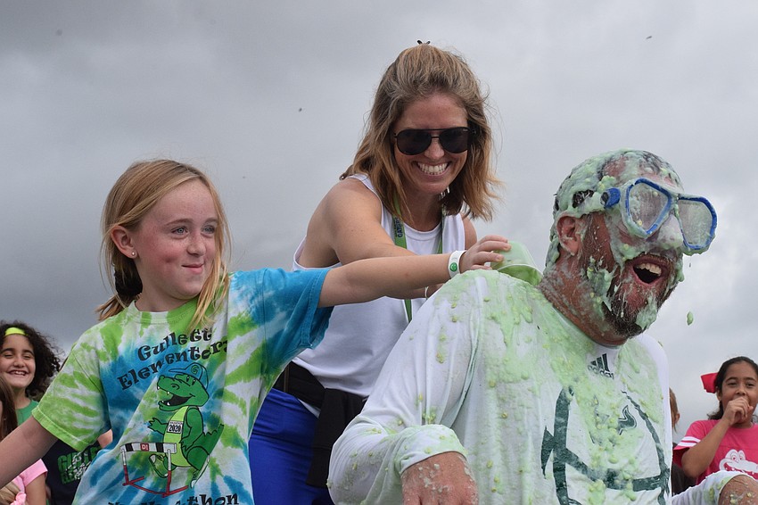 Third grader Sydney Lucas gets help from Parent-Teacher Organization President Kristin Pomeroy, to pour slime down Principal Todd Richardson's shirt.