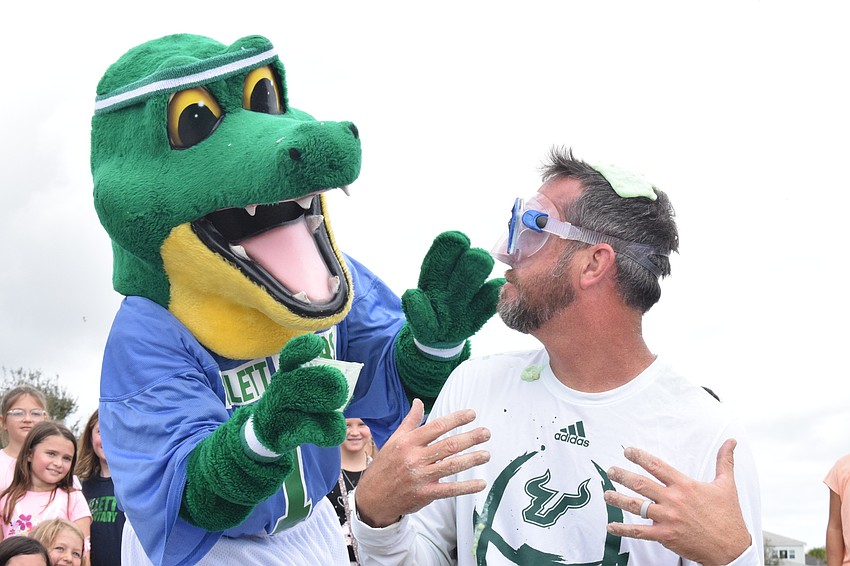 Chompy, B.D. Gullett Elementary School's mascot, and Principal Todd Richardson look at each other after Chompy pours slime on Richardson's head.