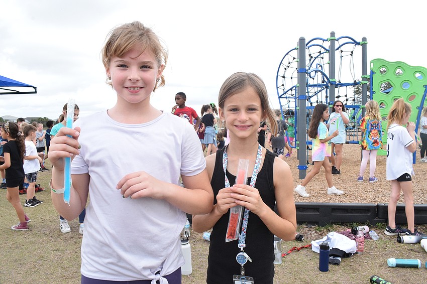 Third graders Olivia Rushmore and Sofia Schultz enjoy popsicles after running and walking a few laps during the walkathon.