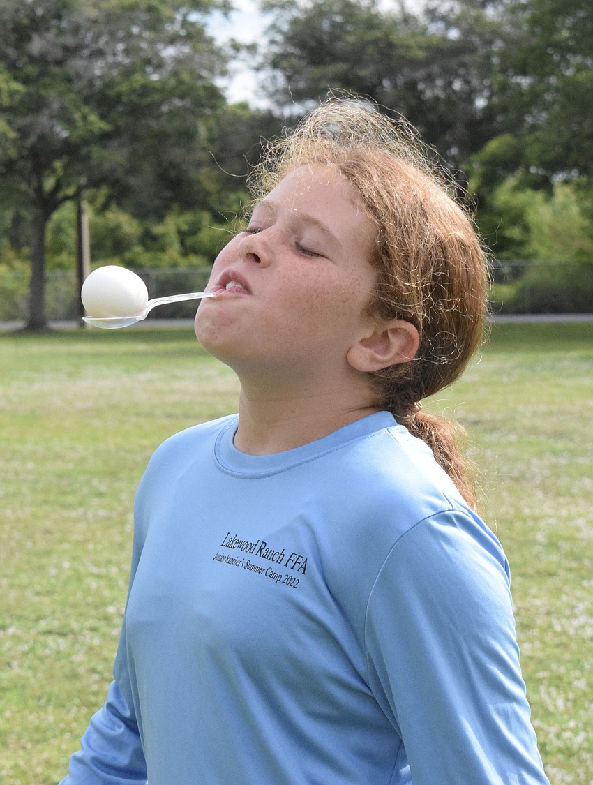 Grace Spibey, a rising fifth grader, carefully balances an egg on a spoon during the relay race. The team activity helped campers learn leadership and teamwork.