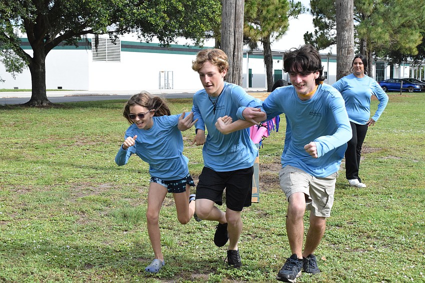 Madison Carlton, a rising fourth grader, Bryon Simon, a rising sophomore, and Talon Tinl, a rising junior, dash for the finish line. They linked arms to show they were a team.