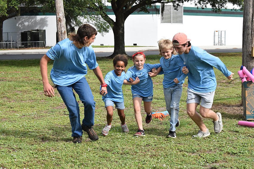 Cody King, a rising senior, Soleil Williams, a rising third grader, Brynn Shear, a rising fifth grader, Brock Sampson, a rising fifth grader, and Max Mangus, a recent high school graduate, link arms as they finish the relay race.