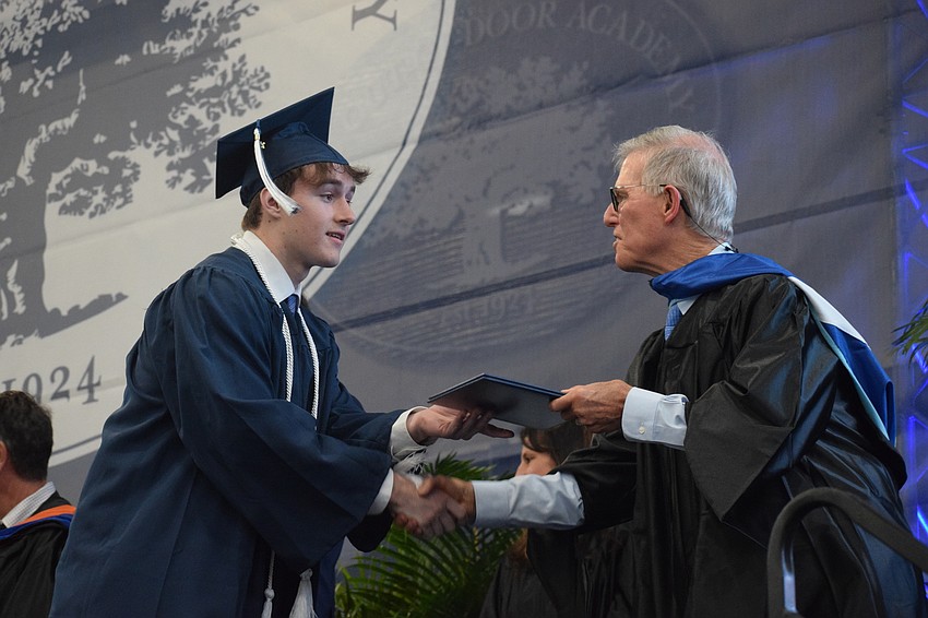 Charles Fioriglio accepts his diploma from James Connor, the interim head of school.