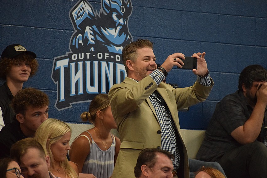 Rick Lamb stands to take pictures and video of his son Ashton Lamb as he walks across the stage to receive his diploma.