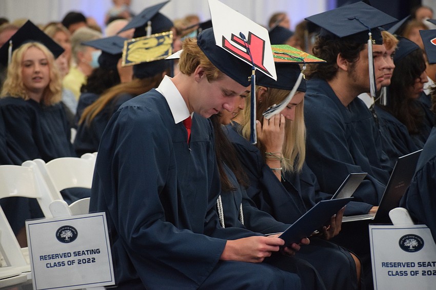 Aidan Murphy looks at his diploma as more graduates' names are called.
