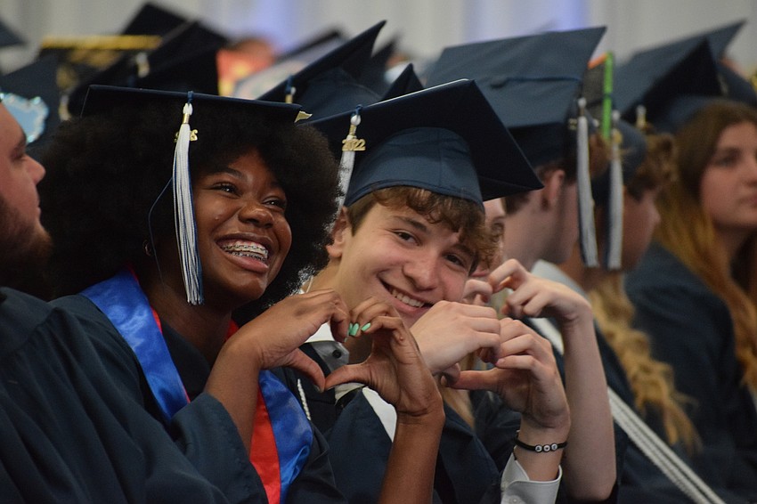 ODA seniors Aaliyaa Genat and Anthony Gaukhman make hearts with their hands as they enjoy their graduation ceremony.