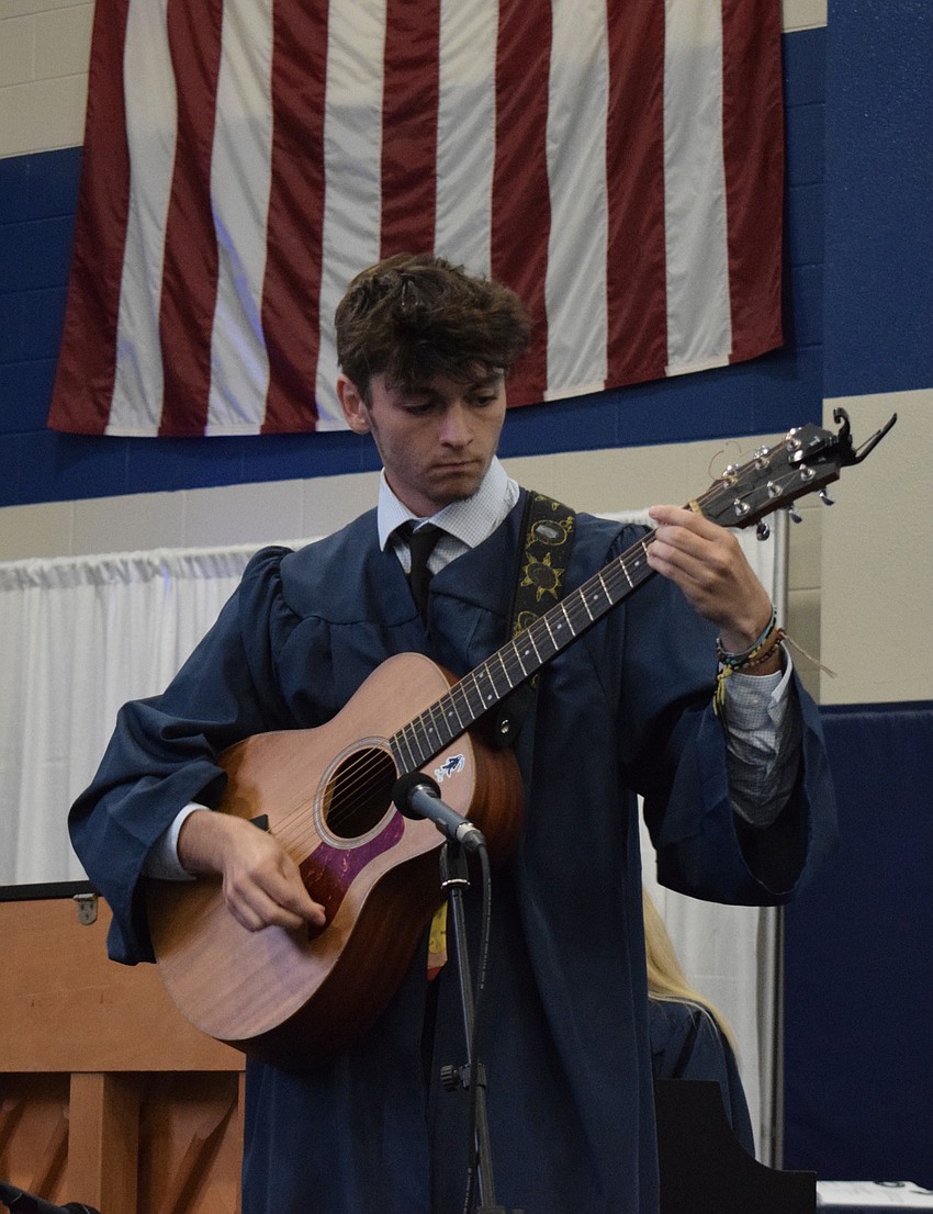 Ryan Newhams plays guitar with seven other graduates as they perform 