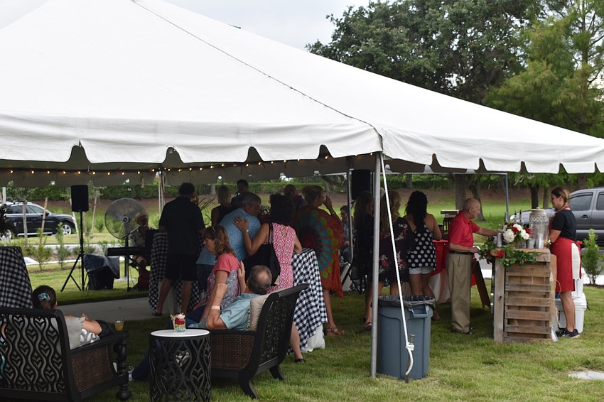 Visitors gather in the tent outside for live music by Kettle of Fish, and catering by Mission BBQ.