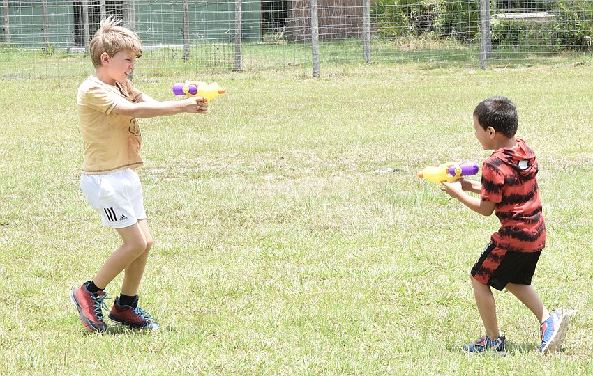 Mateo Murariu, who is 8, tries to squirt water on Bjorn Welde-Thomas, who is 6. Campers went on to play with water balloons, sing karaoke and participate in other activities.
