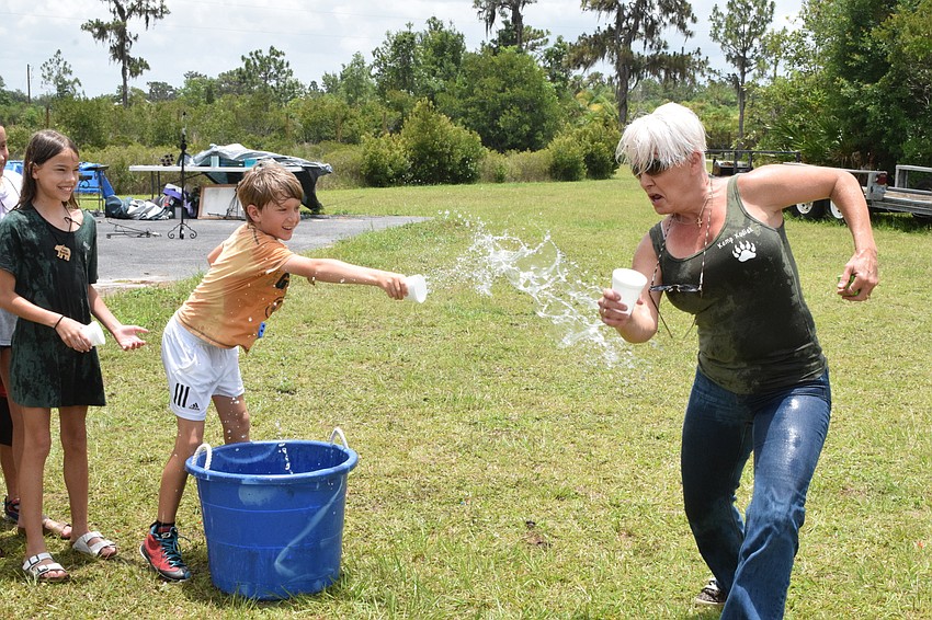 Mateo Murariu, who is 8, tries to throw water onto Renee Riddle, who is a camp leader.