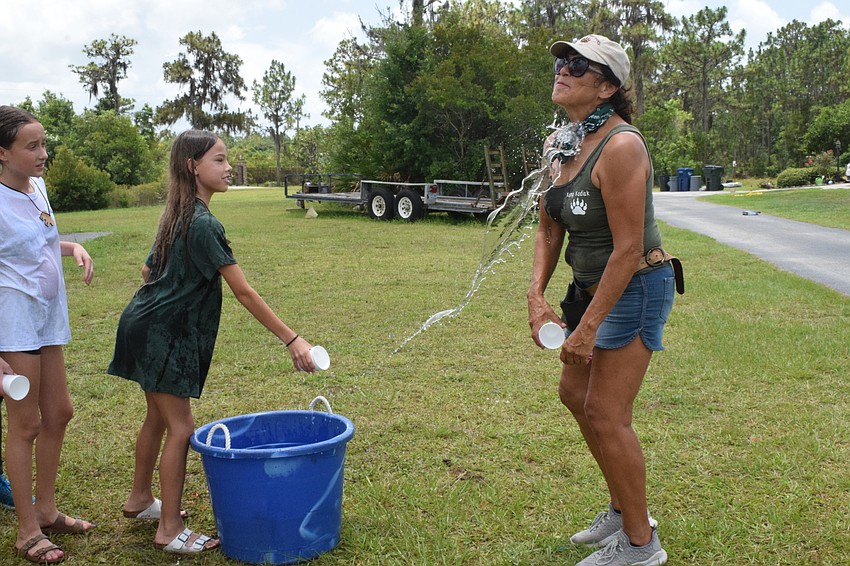 Sidney Lamarre, who is 11, has fun playing a dice game that results in splashing other campers and Monica Welde, the owner of Bearadise Ranch, with water.