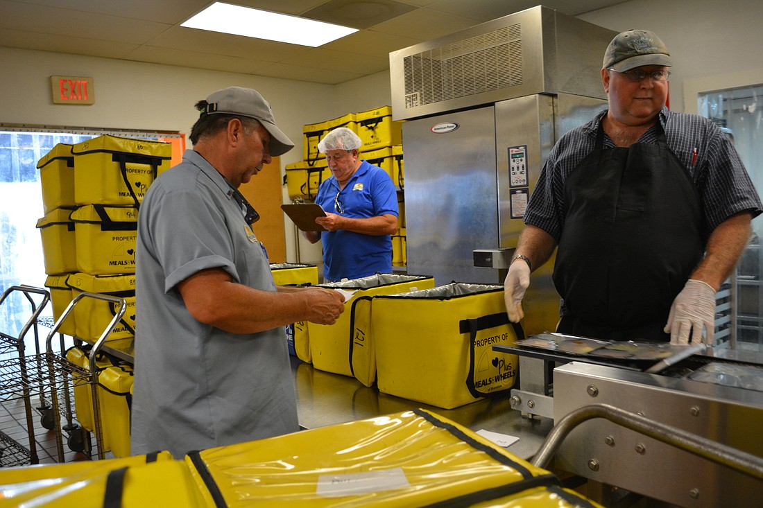 Meals on Wheels PLUS driver Steve Gadberry, left, helps prepare bags of hot meals at the Meals on Wheels kitchen, in Bradenton. File photo.