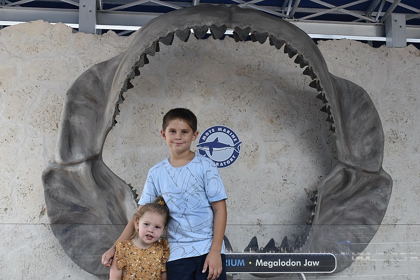 Austin and Amelia Horton stand in front of a giant megalodon jaw.