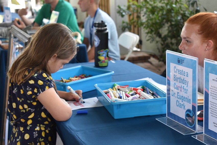 Volunteer Catie Larsen helps Vivien Scheufler make a birthday card for Eugenie Clark.