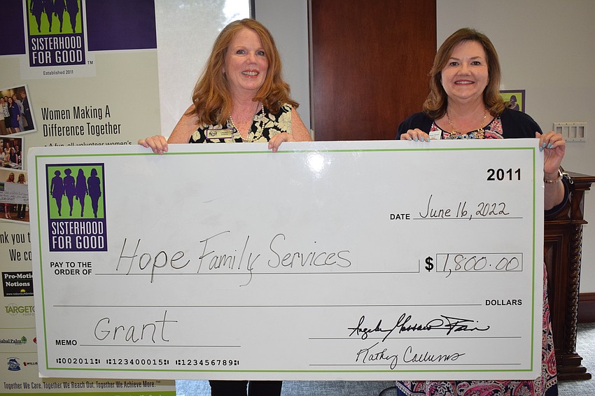 Hope Family Services' Laurel Lynch receives the big check from Sisterhood for Good's Morgan Gerhart.