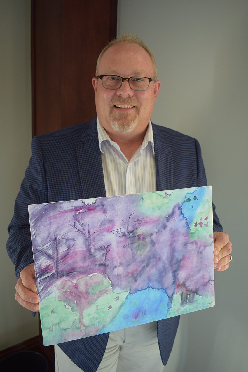 Douglas Staley, the CEO of Child Protection Center, shows a painting made by a child who now is seeing the world in a brighter light.
