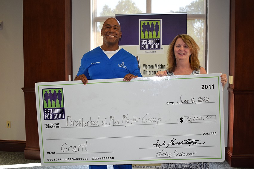 Dr. Dwight Fitch receives a big check of $2,000 for The Brotherhood of Men Mentor Group from Sisterhood for Good's Amy Gorman.