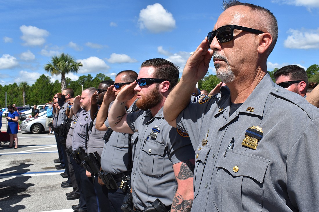 Daytona Beach Police officers salute the flag. Courtesy of DBPD