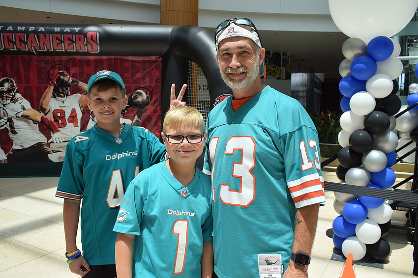 Venice's Cody Kovacs throws a football around with his friend Zachary Frady and Frady's father, Dusty Frady. They all wore Dolphins jerseys to show support for their favorite football team.