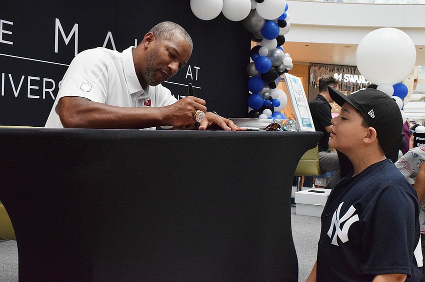 Alex Smith, a former player for the Tampa Bay Buccaneers, signs a photo for Port Charlotte's Evan Morales, who is 10. Morales has been a Buccaneers fan for three years.
