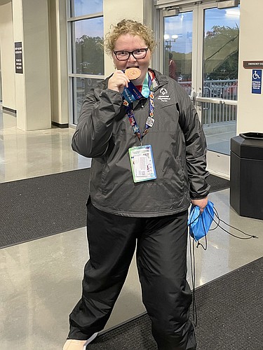 Mary Russell, 24, takes a bite of her gold medal at the 2022 Special Olympics USA Games. Russell won the women&#39;s 100 yard freestyle (1:30.34). (Courtesy photo)