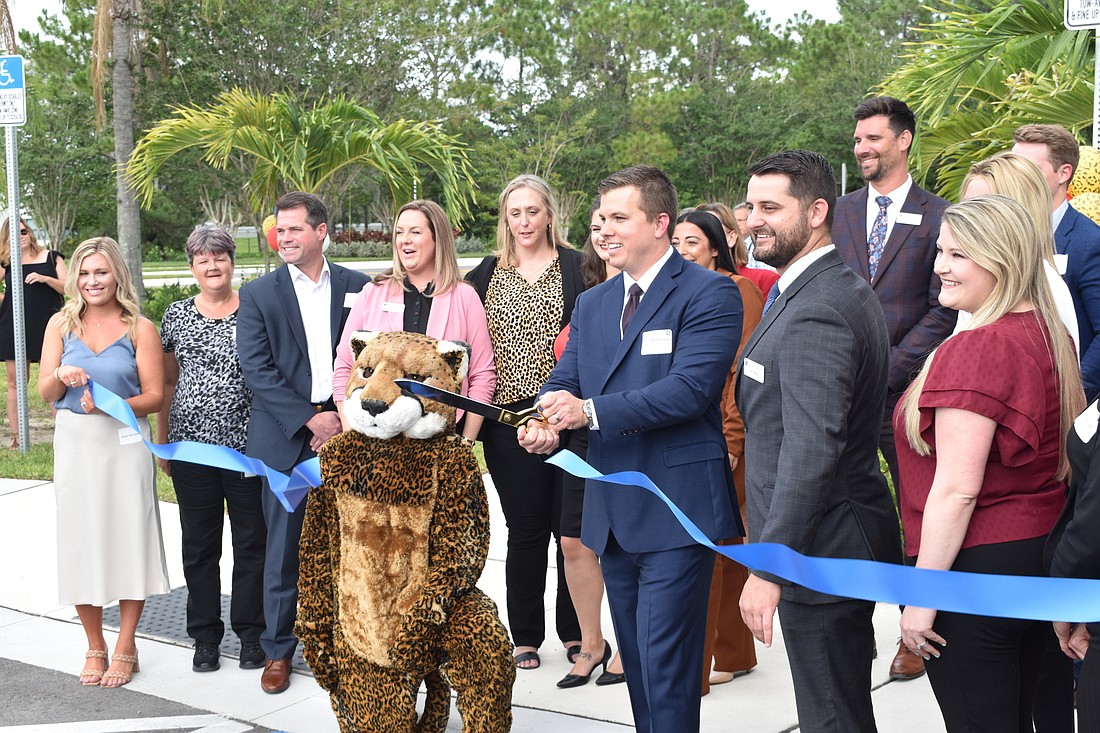 Tyler McCallister cuts the ribbon during the grand opening of Brown & Brown Insurance. (Photo by Ian Swaby)