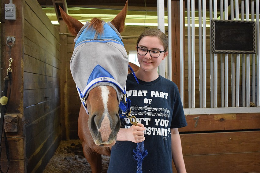 Ellianna Rogers, who is 14, brings Tilly out of her stall so they can head to the arena. The SMART camp is the first time Rogers has been able to ride a horse.