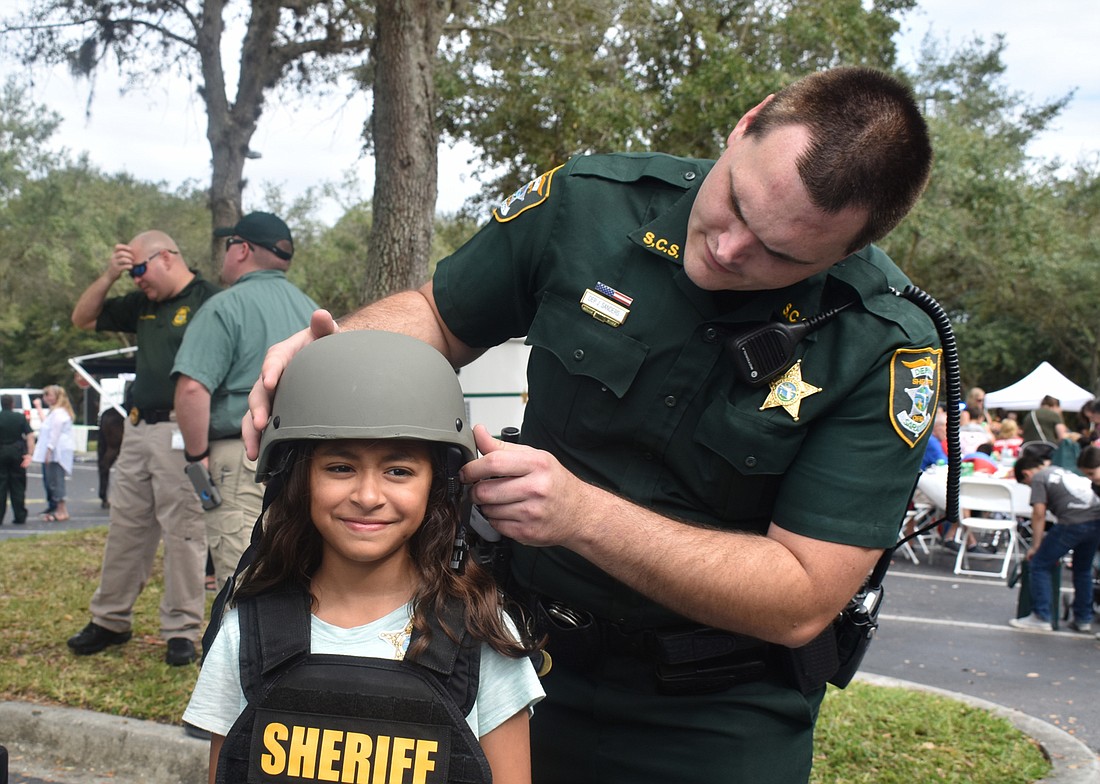 Deputy Josh Sanders helps Sophia Castellanos try on a helmet at a recent open house at the headquarters of the Sarasota County Sheriff&#39;s Office.