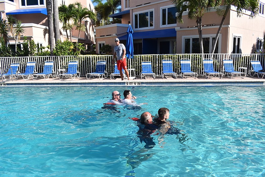 Timothy Haas, Jason Berzowski, Jeff Bullock, and Ryan Corso practice life-saving drills in the pool.