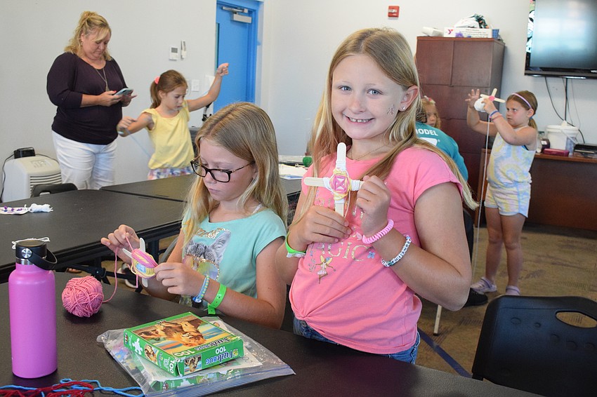 Mia Morgan and Emma McGlaughlin work on their craft projects during the YMCA's specialty camp, Kids Gone Crafty. McGlaughlin says she loves using yarn in her crafts.