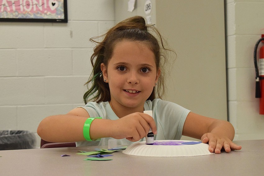 Kendall Marks has fun using green and purple paper to cover her turtle's shell. The campers are making turtles because the theme of the week is 