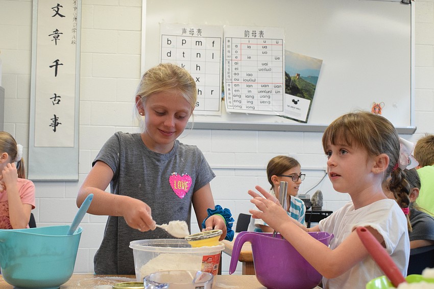 Paige Royce, who is 8 years old, and Dolly Rees, who is 6, laugh while trying not to get flour on themselves.