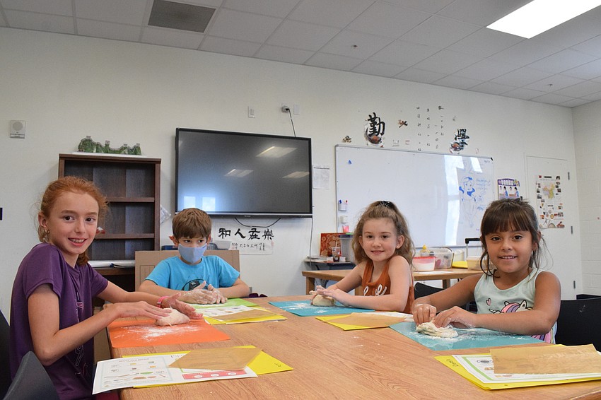 Julia Oliveira, who is 10, Joshua Rodriguez, who is 6, Riley Patterson, who is 9, and Alessia Enciso, who is 6, have fun kneading their dough. They had to add more flour so the dough wouldn't stick to their hands as much.