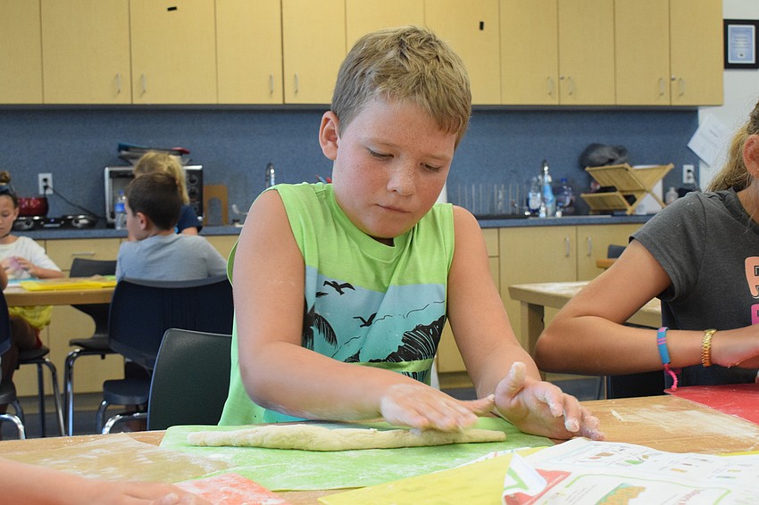 Easton Gillespie, who is 9 years old, kneads his dough out to be the length of his board.