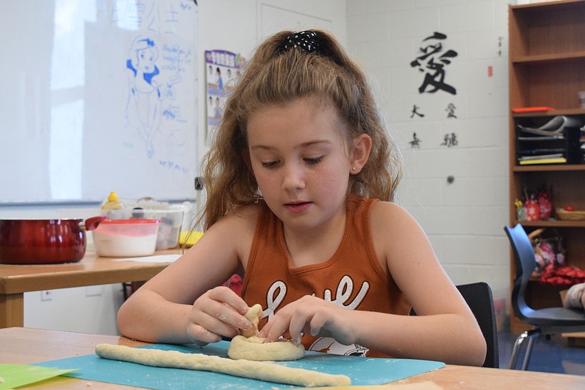 Riley Patterson, who is 9, attempts to make a pretzel shape with her dough. She smiles after seeing it come together.